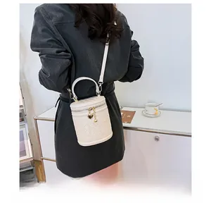 Photo lifestyle d'un sac seau blanc tressé avec breloque cœur et bandoulière