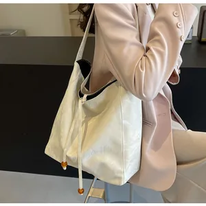 Detalle de bolso tote crema con cordón de cuentas de ámbar en un entorno de estilo de vida