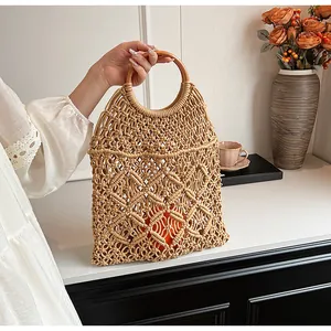 Detalle de bolso de playa tejido a mano con asas redondas de madera y diseño calado
