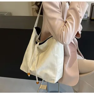 Detalle de bolso tote blanco efecto mármol con cuentas naranjas en el cordón