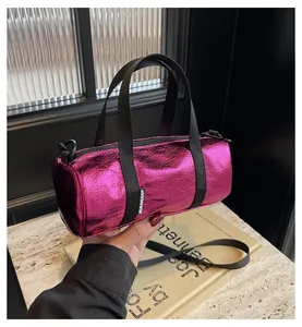 Metallic pink cylindrical pillow bag with wrinkled texture and stylish black hardware