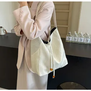 Detalle del bolso tote crema con textura plisada, cordón y detalles de cuentas ámbar