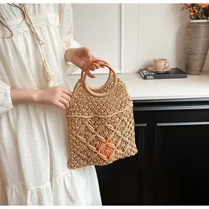 Detalle de bolso de malla tejida a mano con asas redondas de madera para el verano