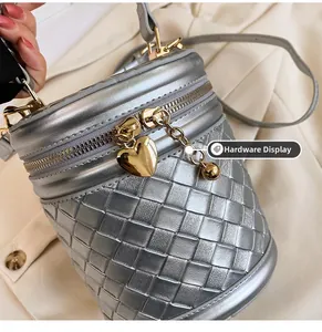 Détail du sac seau tressé argenté avec ferrures dorées et pendentifs en forme de cœur