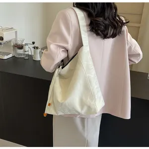 Detalle del bolso tote crema con textura arrugada y cuenta de ámbar en cordón