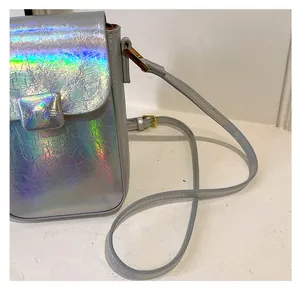 Detail of holographic mini crossbody bag with pleated texture and silver strap