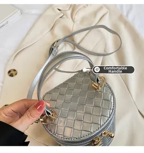 Détail du sac seau tissé argenté avec poignée ronde et finitions dorées sur un manteau