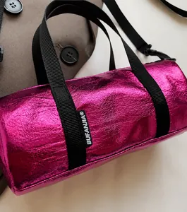 Close-up of metallic pink cylindrical bag with glossy finish and brand logo label