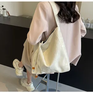 Detalle del bolso tote blanco crema con superficie texturizada y colgante de cuentas naranja
