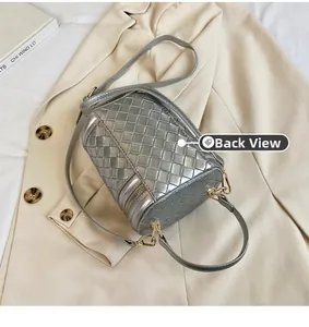 Vue détaillée du sac seau cylindre tressé argenté avec texture métallique et crochets dorés