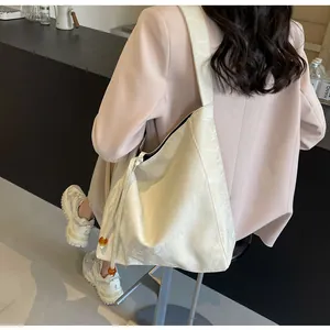 Detalle del bolso tote crema con textura plisada y cordón lateral con cuentas de ámbar