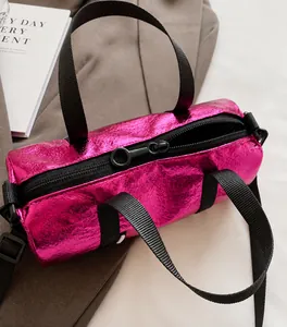 Close-up of metallic magenta barrel bag with crinkled texture and black handles