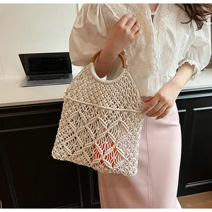 Detalle del bolso de playa de macramé tejido a mano blanco con asas redondas de madera