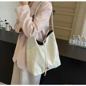 Detalle de bolso tote crema minimalista con cordón ajustable y cuentas de ámbar