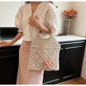 Detalle de bolso de malla beige tejido a mano con asas redondas de madera y diseño calado