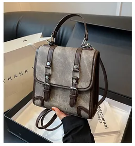 Detail of vintage gray canvas satchel with brown leather trim and silver buckles in box