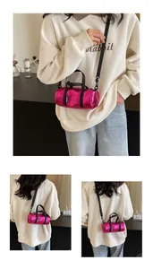 Macro view of metallic magenta duffel bag showing black straps and side label detail
