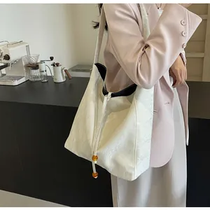 Detalle del bolso tote de cuero crema con forro negro en contraste y correa ancha de hombro