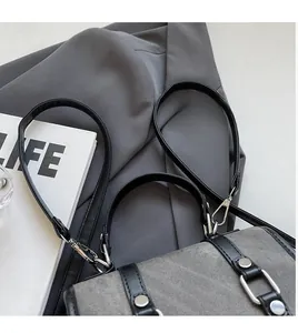Detail of dark grey canvas tote with black leather straps and silver metal buckle accents