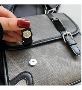 Close-up of vintage canvas messenger bag with silver magnetic buckle and leather trim