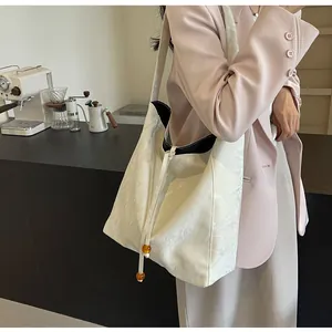 Detalle del bolso tote blanco roto con textura plisada y cordón con cuentas de ámbar