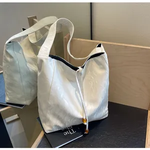 Detalle del bolso tote blanco con textura de mármol, cordón y cuentas de ámbar