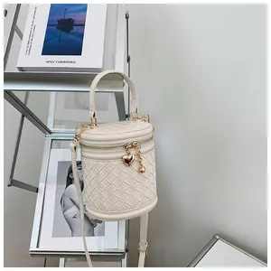 Détail du sac seau tressé beige avec pendentifs cœurs dorés et poignée supérieure