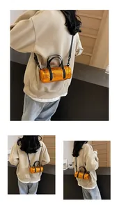 Detailed macro view of the metallic orange cylinder bag with black strap and textured finish