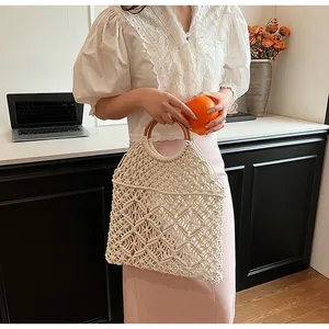 Detalle del bolso tejido a mano crema con patrón de celosía y asas redondas de madera