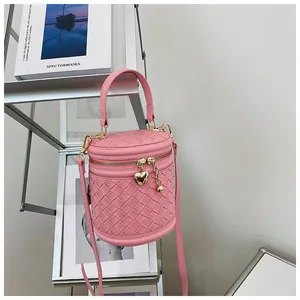 Détail du sac seau tressé rose avec pendentif coeur doré et fermeture zippée en métal