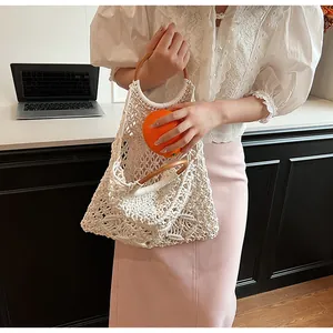 Detalle del bolso de red tejido a mano con asa redonda de madera y textura de malla beige