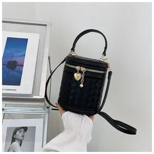 Détail du sac seau tressé noir avec fermeture éclair dorée et breloques en métal