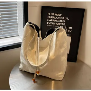 Detalle del bolso tote crema con textura arrugada brillante y cordón con cuentas