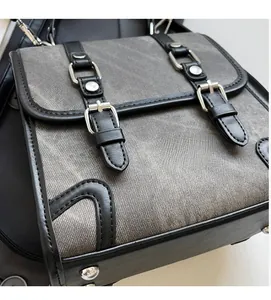 Detail of grey washed canvas and black leather strap closure on a retro backpack