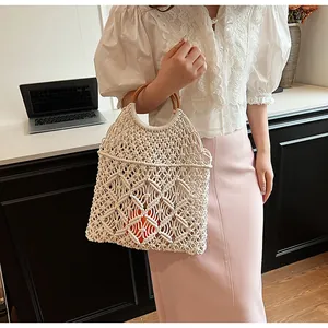 Detalle del bolso de macramé blanco hecho a mano con asas de madera redondas y diseño calado