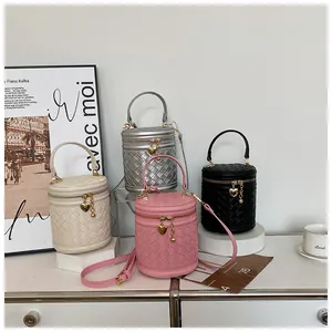 Détail de sacs seaux tressés multicolores avec breloque cœur et bandoulière exposés