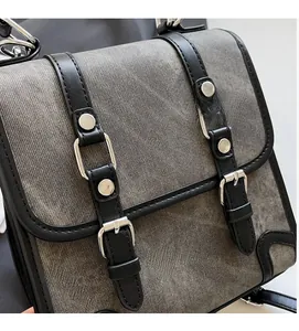 Detailed view of grey denim backpack with black leather straps and silver buckles