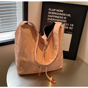 Detalle del bolso plisado rosa con cordones de cuentas de ámbar y textura de cuero PU metal