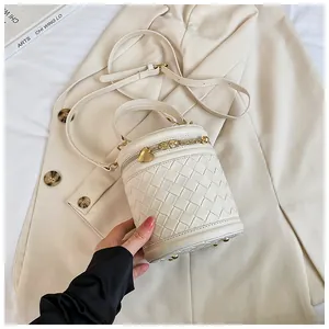 Détail d'un sac seau tressé crème avec fermeture éclair cœur doré et bandoulière