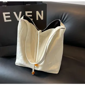 Detalle de bolso tote blanco roto brillante con cordón de cuentas ámbar y textura