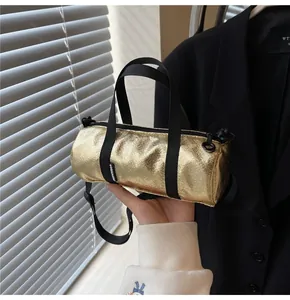 Close-up of metallic gold cylinder bag featuring nylon straps and pleated leather texture