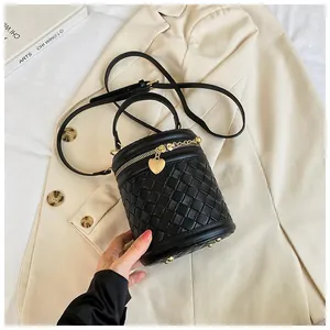 Détail du sac seau tressé noir avec fermeture éclair dorée et pendentif en forme de cœur