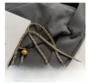 Close-up of golden chain strap with adjustable quilted metal ball on blue woven bag