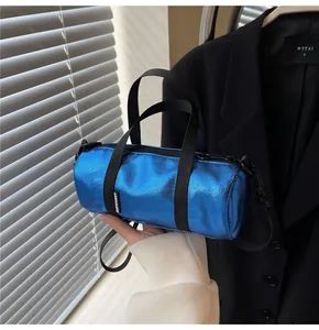 Detail of blue metallic cylinder bag with nylon handles and adjustable shoulder strap