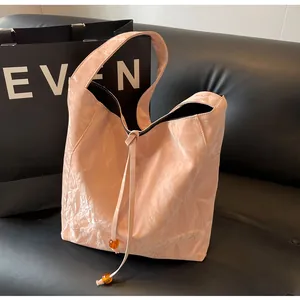 Detalle de bolso tote rosa arrugado con cierre de cordón y cuentas de ámbar finas