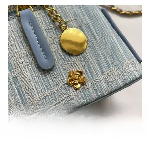 Close-up of blue tweed bucket bag with gold flower buckle and metallic chain strap