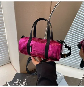 Detailed view of mini metallic magenta cylinder bag with nylon straps and brand label