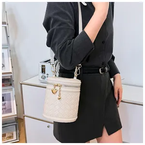 Détail du sac seau en cuir tressé crème avec breloque cœur dorée et fermeture éclair