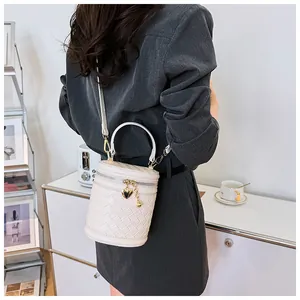 Détail du sac seau blanc tressé avec pendentif coeur doré et fine bandoulière chic