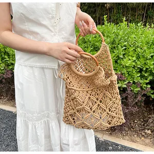 Detalle del bolso tejido a mano con asas redondas de madera y patrón de malla calada